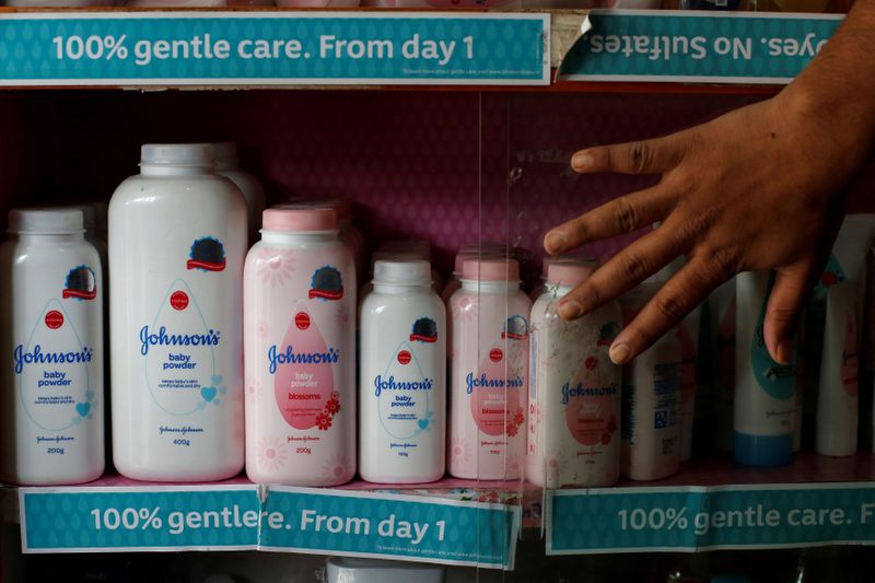 © Reuters. FILE PHOTO: A worker closes a glass cabinet of Johnson & Johnson baby powder bottles at a medical store in Kolkata