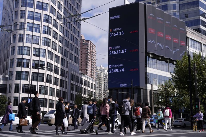 &copy; Reuters. People wearing masks, following the coronavirus disease (COVID-19) outbreak, walk past a building with electronic board showing world stock indexes, in Shanghai