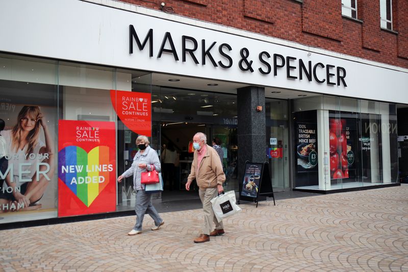 &copy; Reuters. Alcune persone con indosso la mascherina passano accanto a uno dei punti vendita di Marks and Spencer (M&amp;S) ad Altrincham