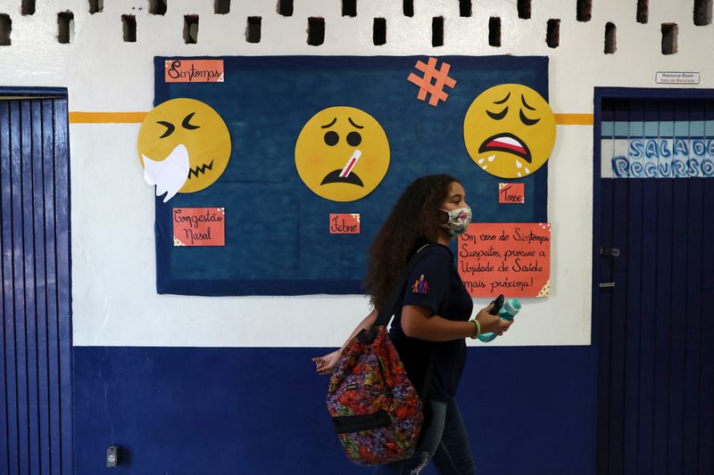 &copy; Reuters. Estudante caminha em frente a painel informativo sobre Covid-19 em São Paulo