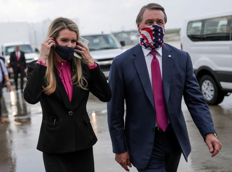 © Reuters. FILE PHOTO: Republican U.S. Senators from Georgia Loeffler and Perdue walk together at Hartsfield-Jackson Atlanta International Airport in Atlanta, Georgia