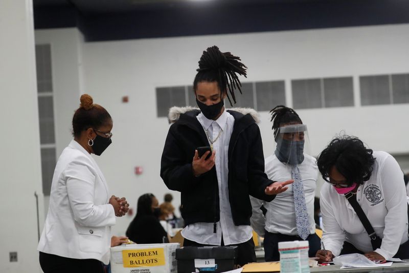 © Reuters. A person holding a cell phone reacts as votes continue to be counted at the TCF Center the day after the 2020 U.S. presidential election, in Detroit, Michigan