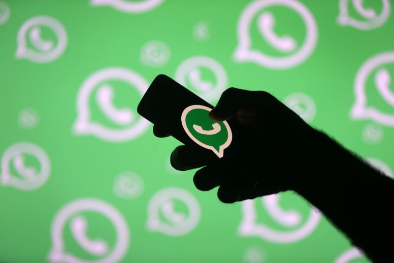 © Reuters. A man poses with a smartphone in front of displayed Whatsapp logo in this illustration