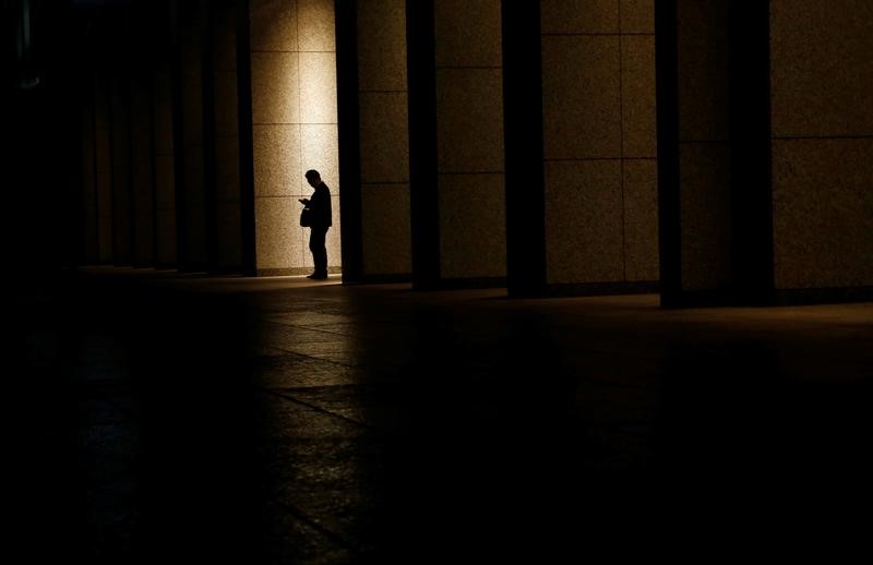 &copy; Reuters. A man is silhouetted at an entrance of a commercial building at closing hour at a financial district in Tokyo
