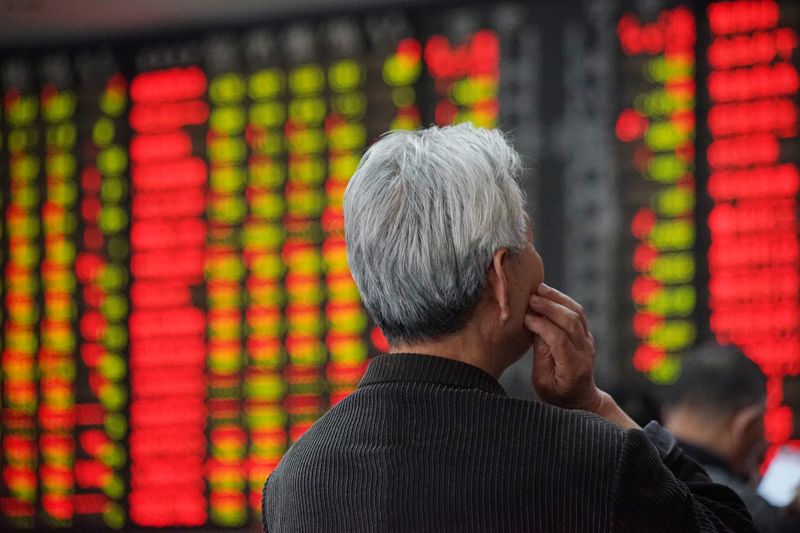 © Reuters. An investor looks at an electronic board showing stock information at a brokerage house in Nanjing