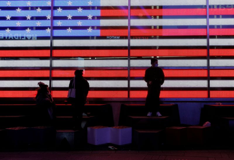 &copy; Reuters. Delle persone fotografate davanti alla bandiera statunitense proiettata a Times Square