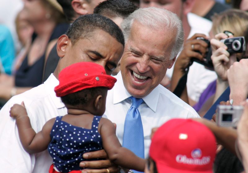 © Reuters. US Democratic presidential candidate Senator Barack Obama holds a child as his vice presidential running mate Senator Joe Biden smiles at a campaign event in Springfield