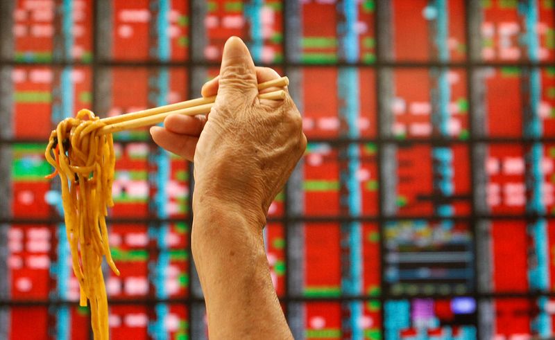 &copy; Reuters. FILE PHOTO: A man eats his lunch of noodles while monitoring stock market prices inside a brokerage in Taipei