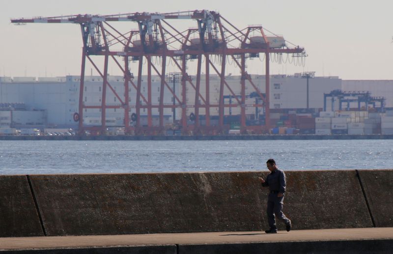 © Reuters. Men are seen in front of containers and cranes at an industrial port in Tokyo