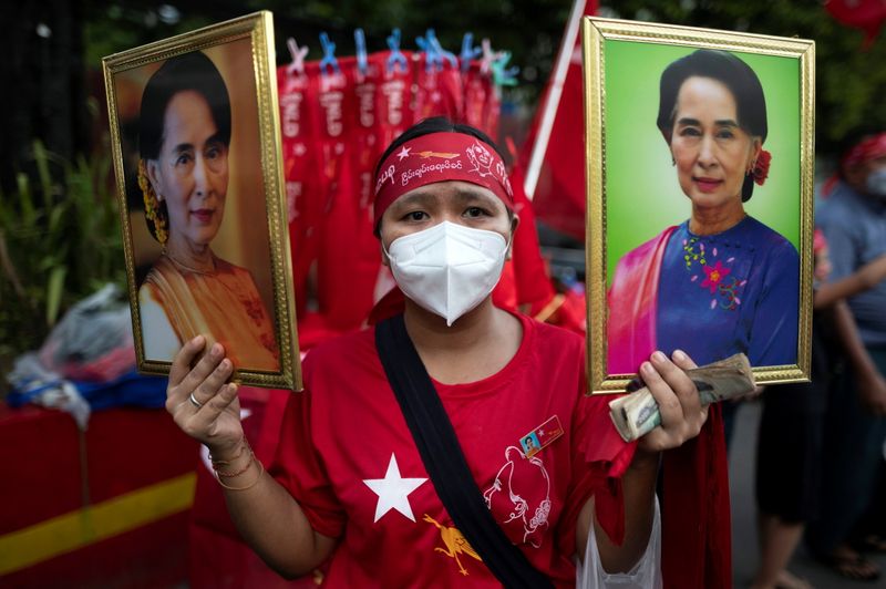 &copy; Reuters. A supporter of National League for Democracy  holds two portraits of Myanmar State Counselor Aung San Suu Kyi  as people gather to celebrate at party headquarters after the general election in Yangon