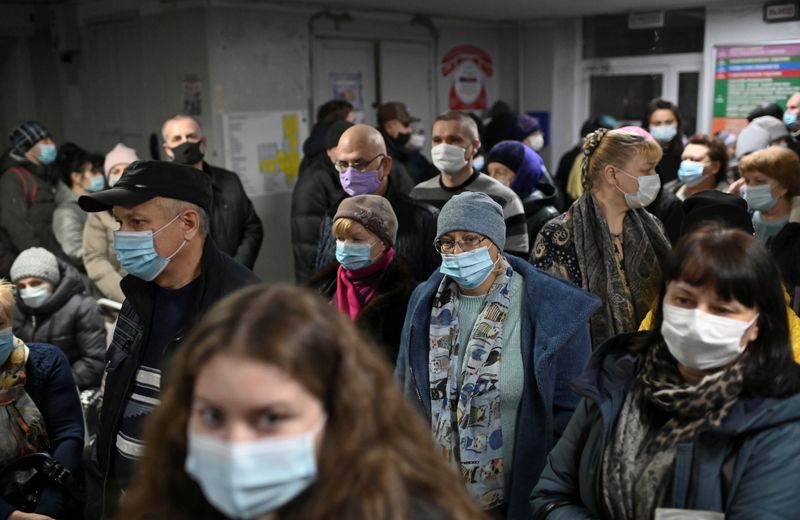 © Reuters. People wearing protective face masks wait in a queue at a clinic in Omsk