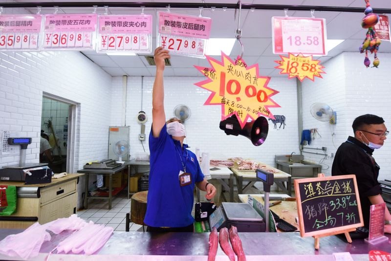&copy; Reuters. Funcionário coloca placa de preço da carne suína em supermercado de Hangzhou, na China