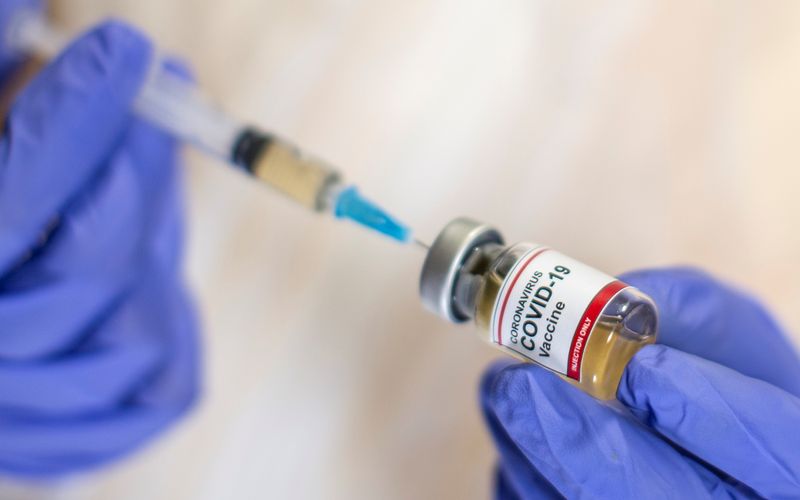 &copy; Reuters. A woman holds a small bottle labeled with a &quot;Coronavirus COVID-19 Vaccine&quot; sticker and a medical syringe in this illustration