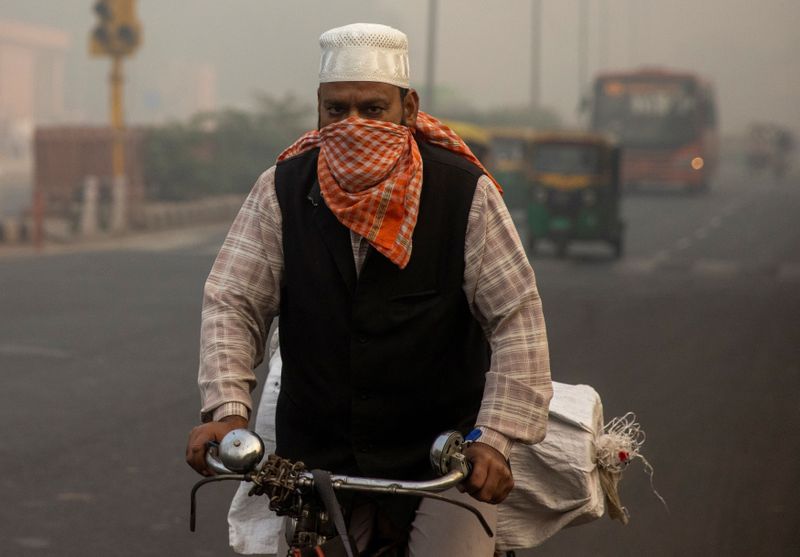 &copy; Reuters. Foto del martes de un hombre transportando bienes en su bicicleta en medio de una nuve de contaminación en Nueva Delhi.