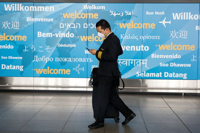 &copy; Reuters. A member of a flight crew wears a face mask as he arrives at John F. Kennedy International Airport in New York