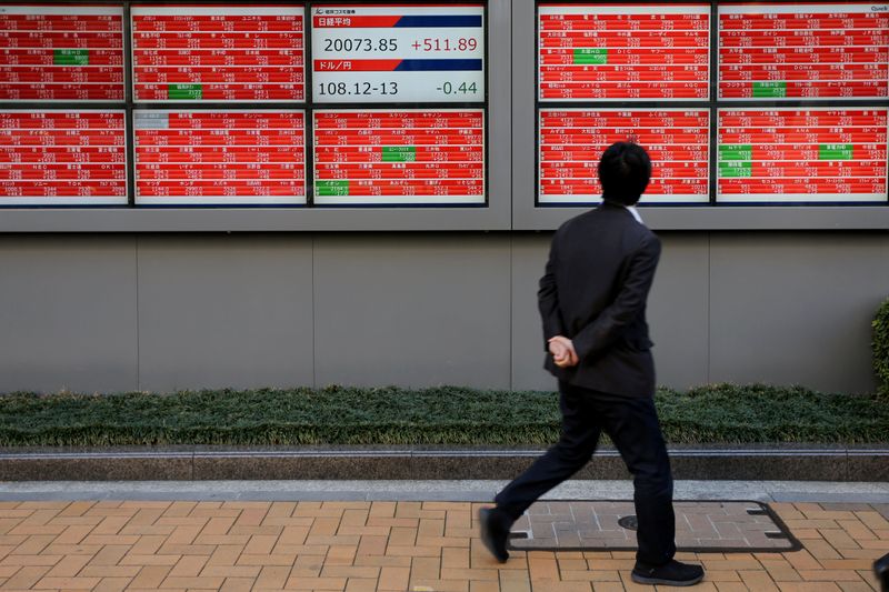 &copy; Reuters. A man looks at an electronic board showing the Nikkei stock index outside a brokerage in Tokyo