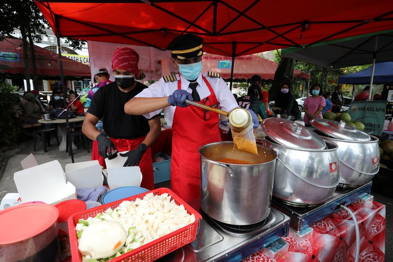 &copy; Reuters. Malaysian former pilot Azrin Mohamad Zawawi prepares food at his food stall in Subang Jaya