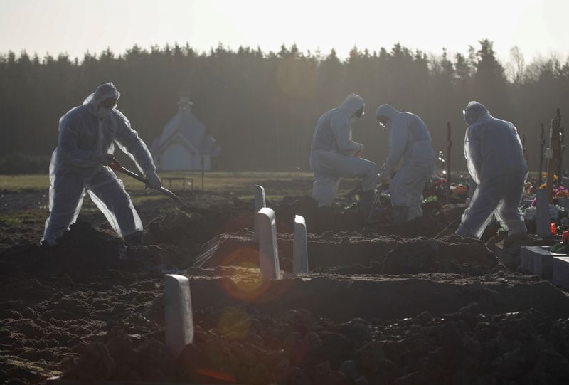 &copy; Reuters. Grave diggers bury a person at a graveyard in Saint Petersburg