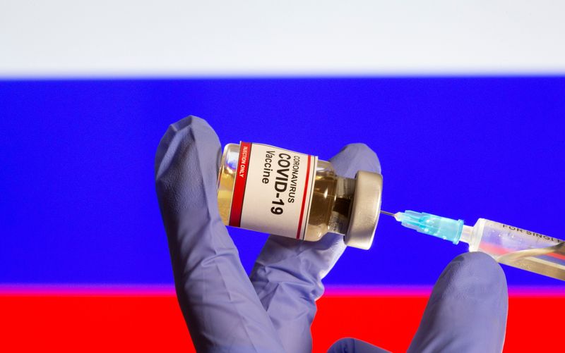 &copy; Reuters. A small bottle labeled with a &quot;Coronavirus COVID-19 Vaccine&quot; sticker and a medical syringe in front of displayed Russia flag in this illustration