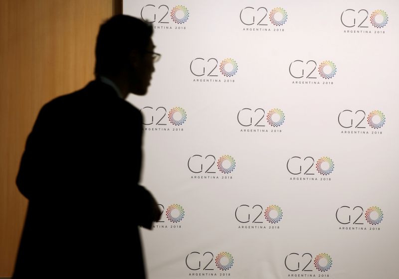 © Reuters. FILE PHOTO: A man stands next to a board with the G20 Meeting of Finance Ministers logo in Buenos Aires