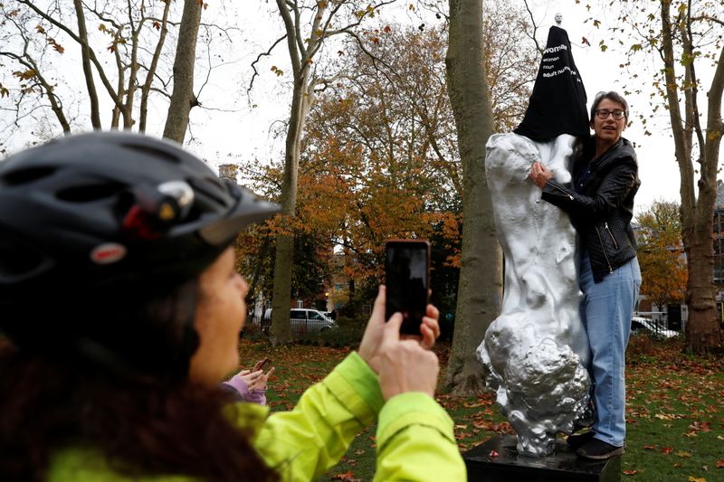 &copy; Reuters. A person takes a photo as a protester covers with a t-shirt the Mary Wollstonecraft statue &apos;Mother of feminism&apos; by artist Maggi Hambling in Newington Green, London