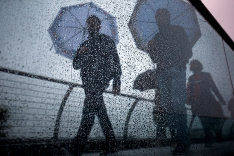 &copy; Reuters. FILE PHOTO: Pedestrians walk across the Millennium Footbridge during rainy weather in London