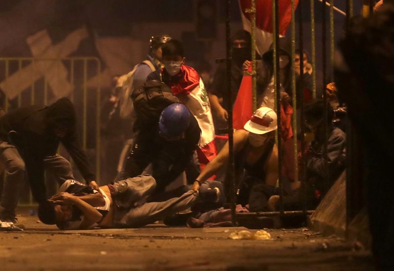 © Reuters. A demonstrator is injured on the ground as he is help by other demontrators during a clash with police during a protest against the decision of Congress to remove former President Martin Vizcarra, in Lima