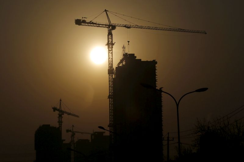 © Reuters. FILE PHOTO: A crane at a construction site is silhouetted against the rising sun in Beijing