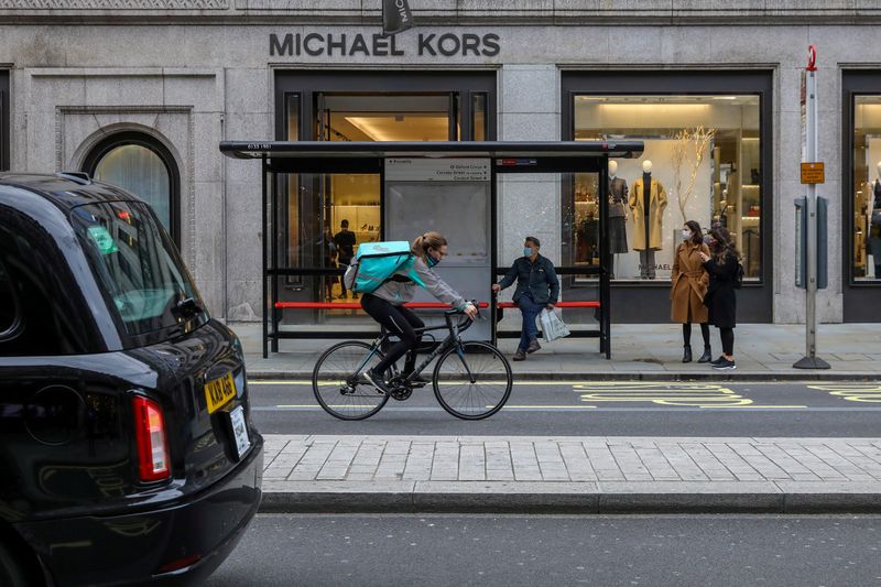 © Reuters. FILE PHOTO: A taxi passes as people wait at a bus stop in Regent Street, London, Britain