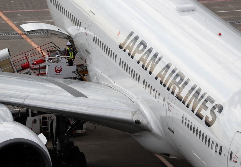 &copy; Reuters. A ground crew of Japan Airlines is seen next to their airplane, amid the coronavirus disease (COVID-19) outbreak, at Haneda Airport in Tokyo