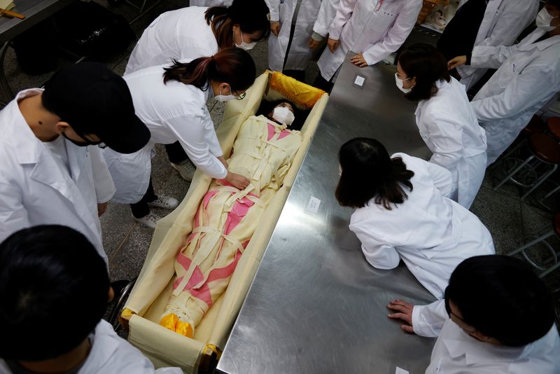 &copy; Reuters. Park Se-jung who majors the funeral directing at Eulji University, is laid in a mock coffin during a class on how to shroud the deceased, in Seongnam