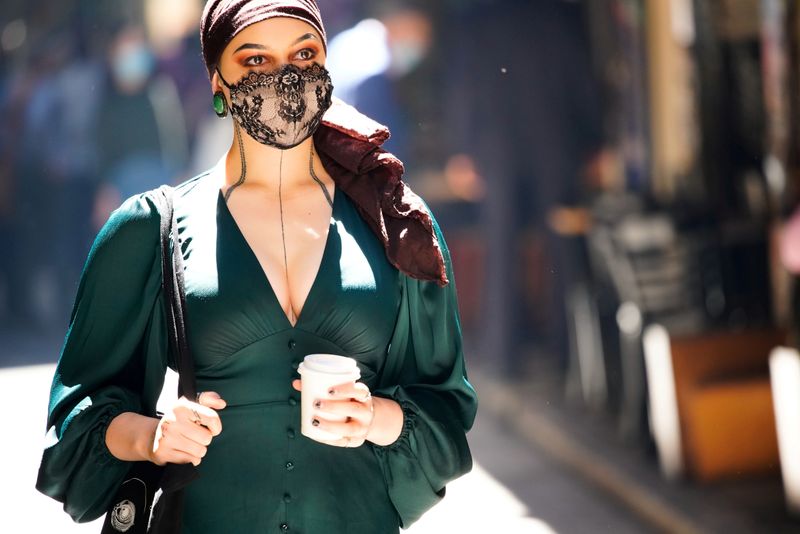 &copy; Reuters. FILE PHOTO: A woman wearing a face masks walks past cafes after coronavirus disease restrictions were eased in Melbourne