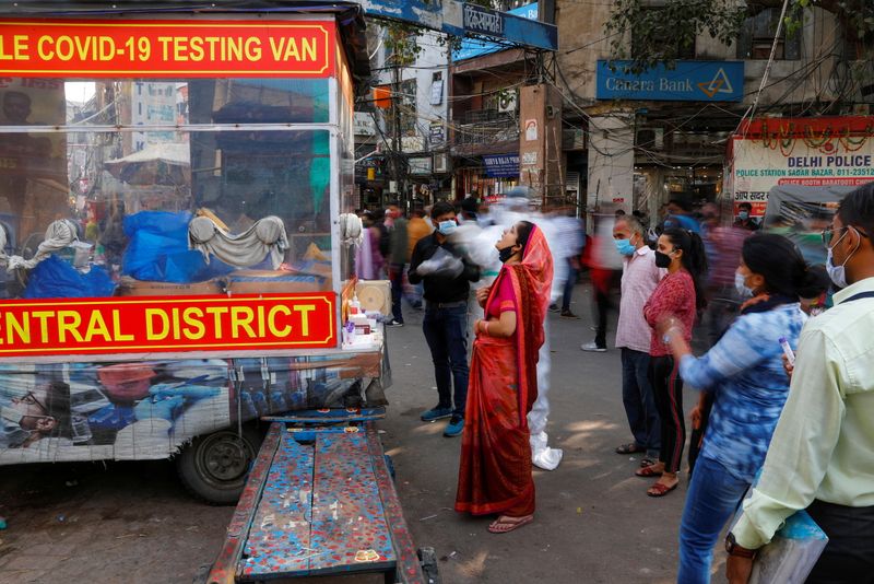 © Reuters. A healthcare worker collects a swab sample from a woman in the old quarters of Delhi