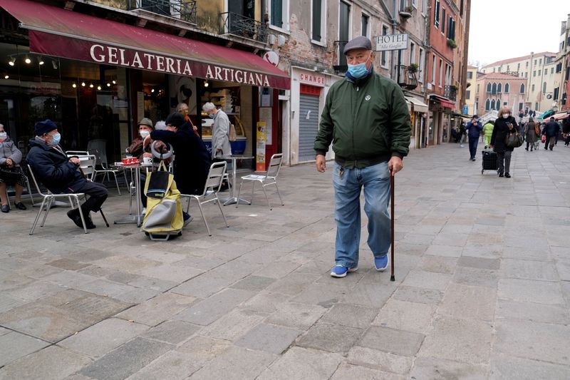&copy; Reuters. Delle persone con indosso la mascherina passeggiano per le strade di Venezia