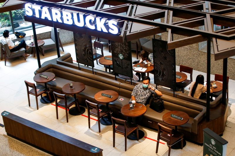 &copy; Reuters. FILE PHOTO: A man wearing a protective mask uses a phone at a Starbucks cafe inside the Indonesia Stock Exchange (IDX) building in Jakarta