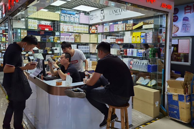 &copy; Reuters. Cosmetics sellers check an order with a customer at the Mingtong Digital City market in Shenzhen&apos;s Huaqiangbei area