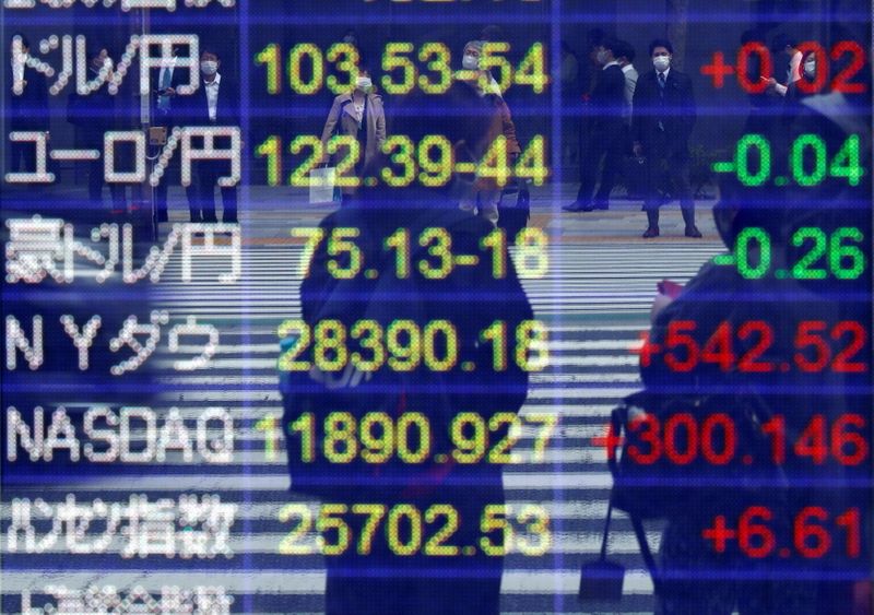 &copy; Reuters. Riflesso di alcuni passanti su uno schermo che mostra il tasso di cambio dello yen giapponese rispetto al dollaro, altre valute estere e gli indici azionari mondiali a Tokyo