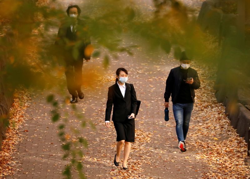 &copy; Reuters. Passersby wearing protective face masks walk under autumn coloured leaves, amid the coronavirus disease (COVID-19) outbreak, in Tokyo