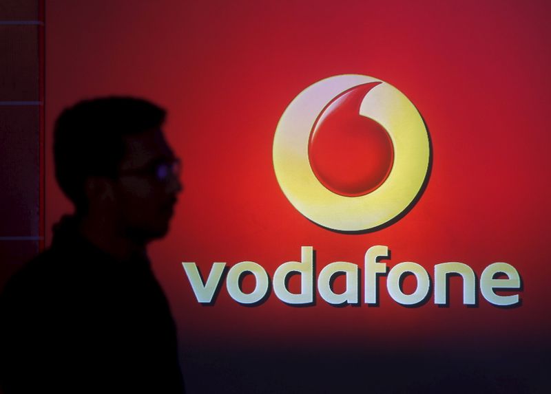 &copy; Reuters. A man casts silhouette onto an electronic screen displaying logo of Vodafone India after a news conference to announce the half year results in Mumbai