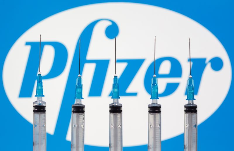&copy; Reuters. Syringes are seen in front of a displayed Pfizer logo in this illustration
