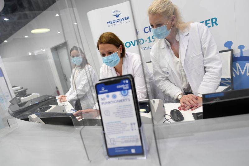 &copy; Reuters. FILE PHOTO: Employees of new COVID-19 quick test center at Franz-Josef-Strauss airport work behind counter in Munich