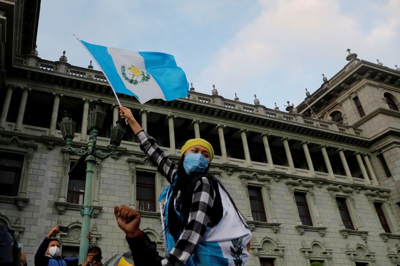 &copy; Reuters. Una mujer sostiene una bandera guatemalteca, durante una protesta para exigir la renuncia del presidente Alejandro Giammattei, un día después de que manifestantes prendieran fuego a una parte del edificio del Congreso en Ciudad de Guatemala