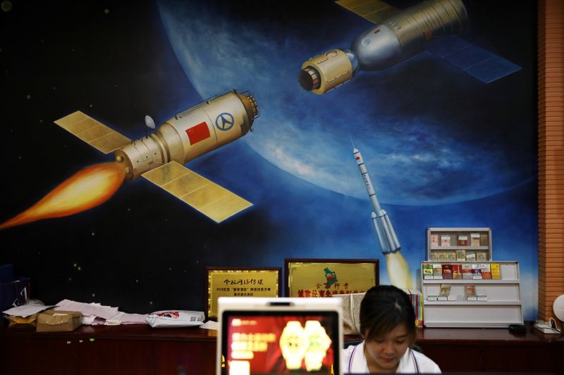 &copy; Reuters. A hotel employee sits in front of a painting depicting a Chinese space mission in Wenchang, Hainan