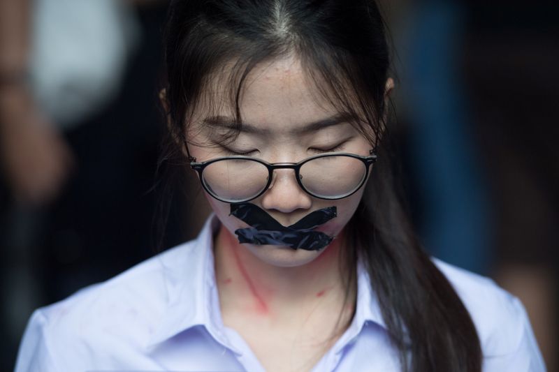 © Reuters. Nalinrat Tuthubthim, 20, a student, who claims she was sexually abused by a teacher, has her mouth covered with tape during a rally in Bangkok