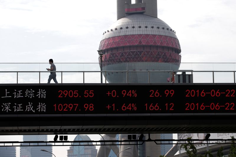 &copy; Reuters. A man walks past electronic board showing benchmark Shanghai and Shenzhen stock indices, on pedestrian overpass at Pudong financial district in Shangha