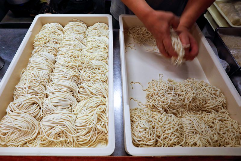 &copy; Reuters. An employee of ramen noodle shop &apos;Shirohachi&apos; prepares noodles inside the shop, managed by sixty-year-old Yashiro Haga, amid the coronavirus disease (COVID-19) outbreak, in Tokyo