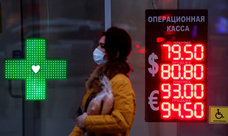 &copy; Reuters. Woman walks past a board showing currency exchange rates of the euro and U.S. dollar against the Russian rouble in Moscow