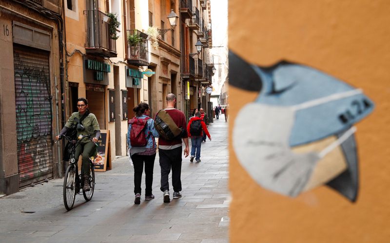 &copy; Reuters. La gente pasan cerca de un dibujo de una persona que lleva una mascarilla, en el centro de Barcelona, España, el 12 de marzo de 2020