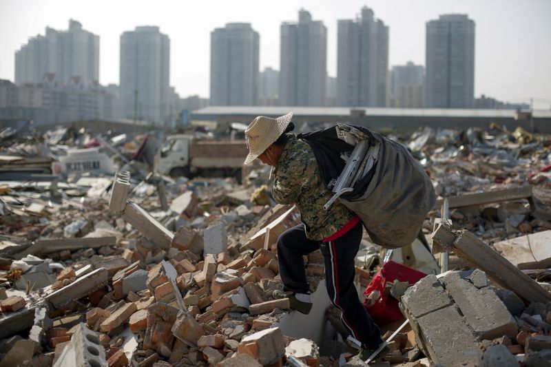 &copy; Reuters. Imagen de archivo de una migrante recogiendo materiales entre los restos de edificios derribados a las afueras de Pekín, China.