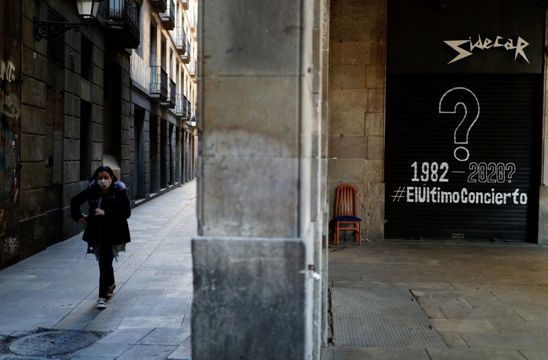 &copy; Reuters. FOTO DE ARCHIVO: Una mujer con mascarilla pasa frente a un bar cerrado en Barcelona